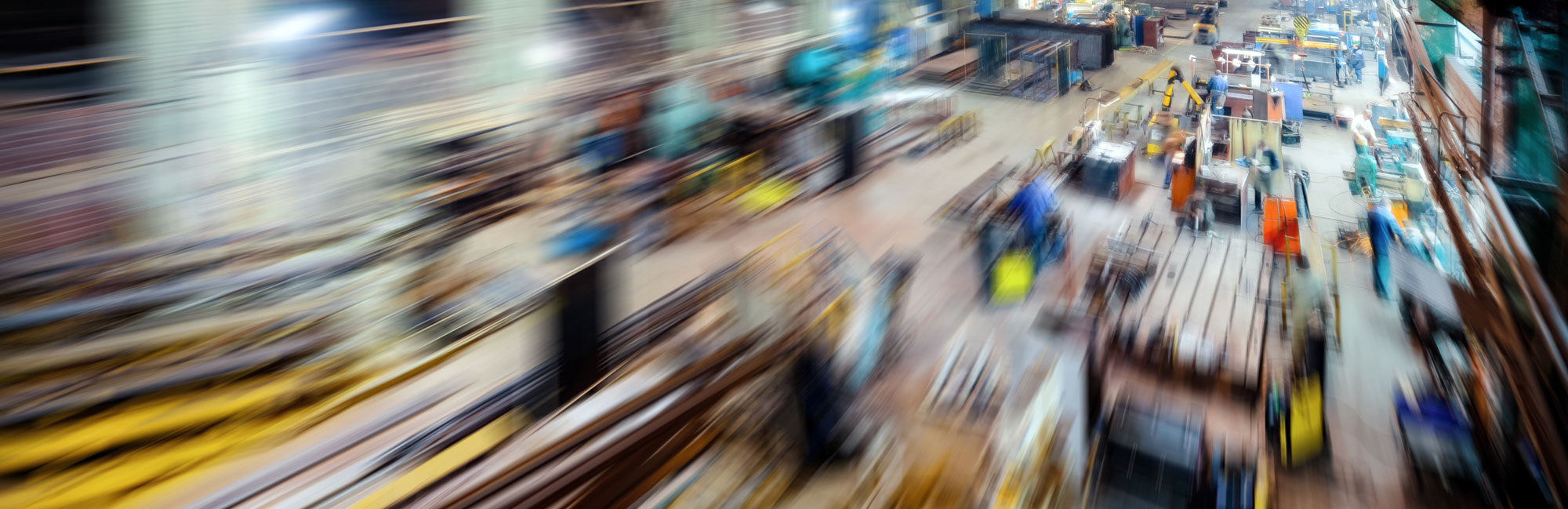 A high-speed motion blur of a busy industrial factory floor, illustrating efficiency, logistics, and large-scale production.