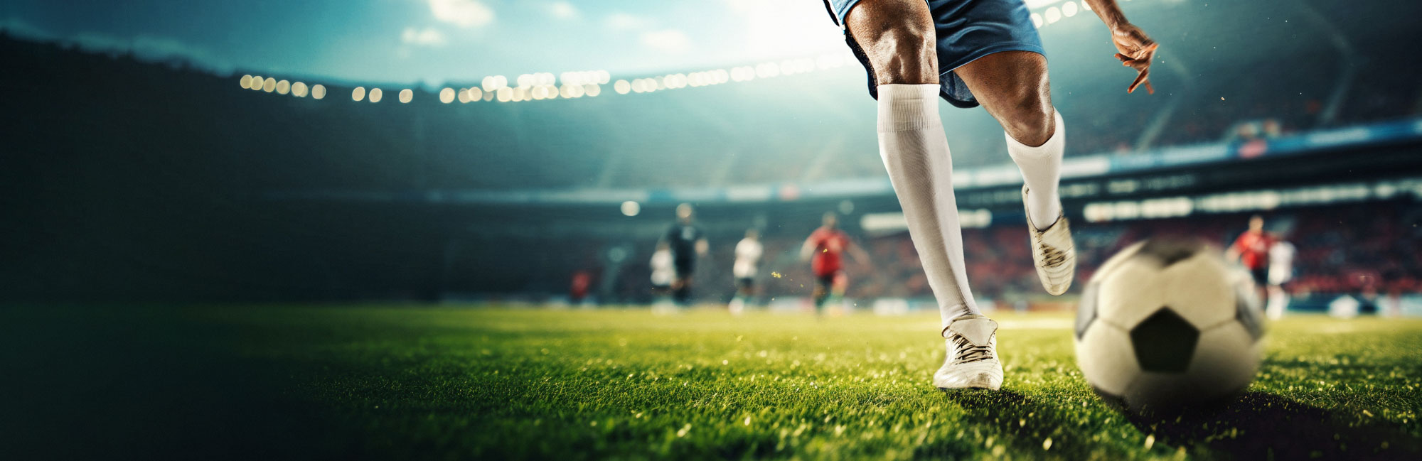 Soccer player dribbling the ball on a professional synthetic turf field in a stadium. The high-performance artificial grass surface ensures durability and optimal playing conditions for competitive sports