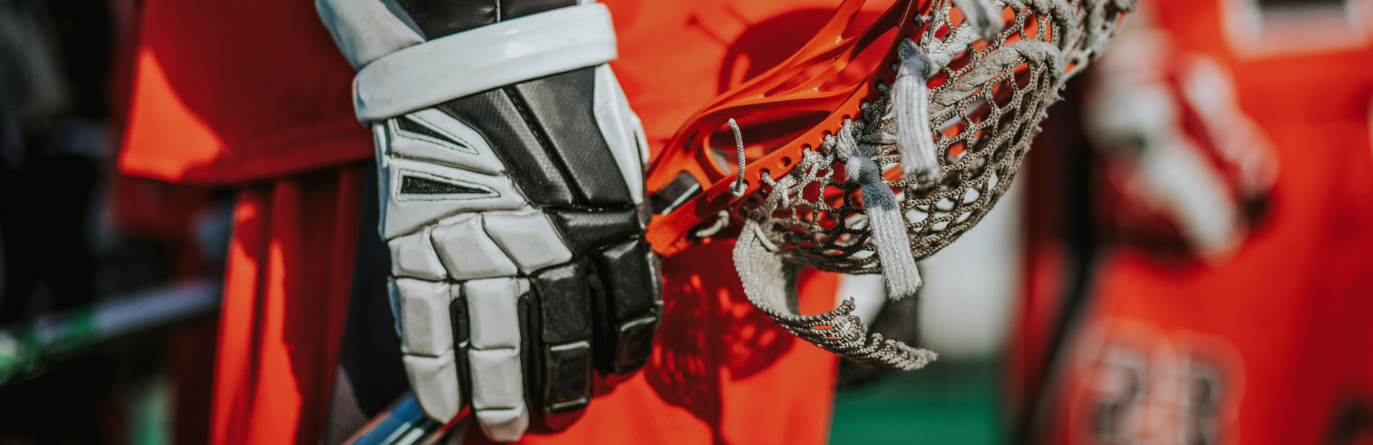 Lacrosse players in red and white gloves gripping their sticks, focusing on teamwork and game strategy.