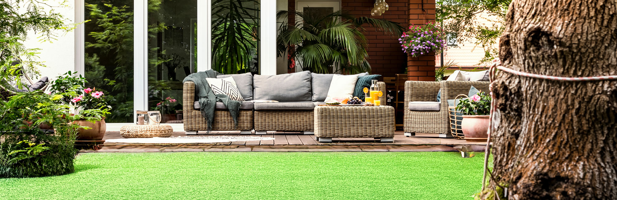 Beautiful backyard with a cozy outdoor seating area surrounded by lush greenery and artificial grass.