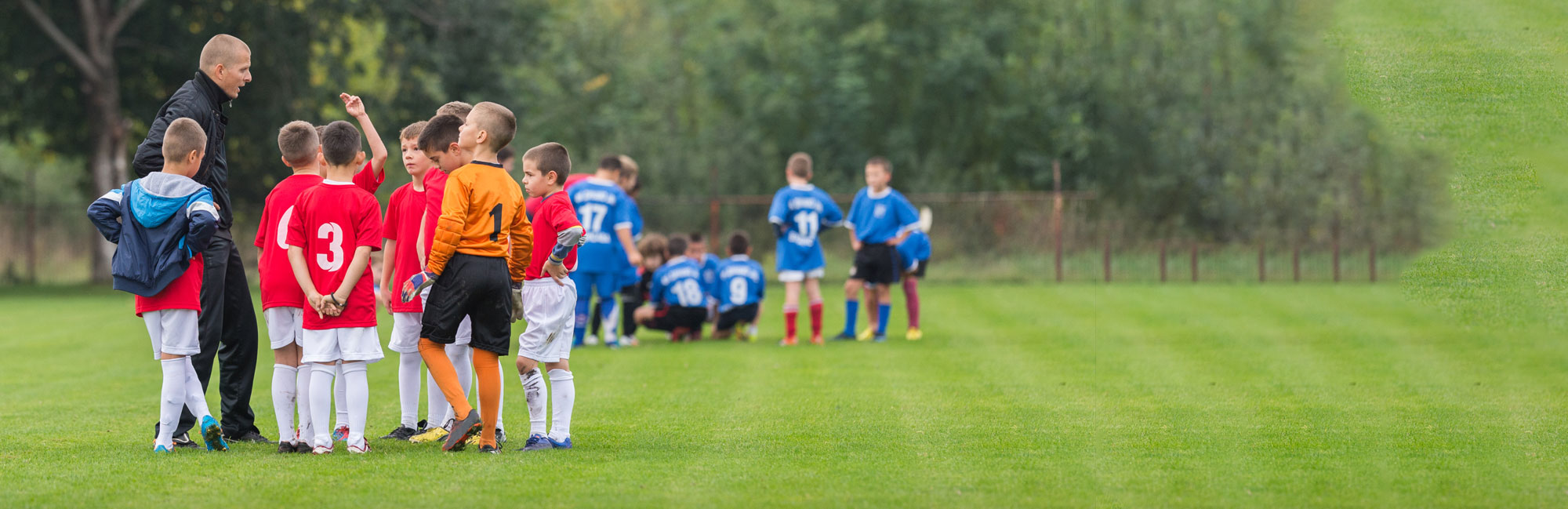 Youth soccer teams gathering on a well-maintained grass field, preparing for a friendly match.
